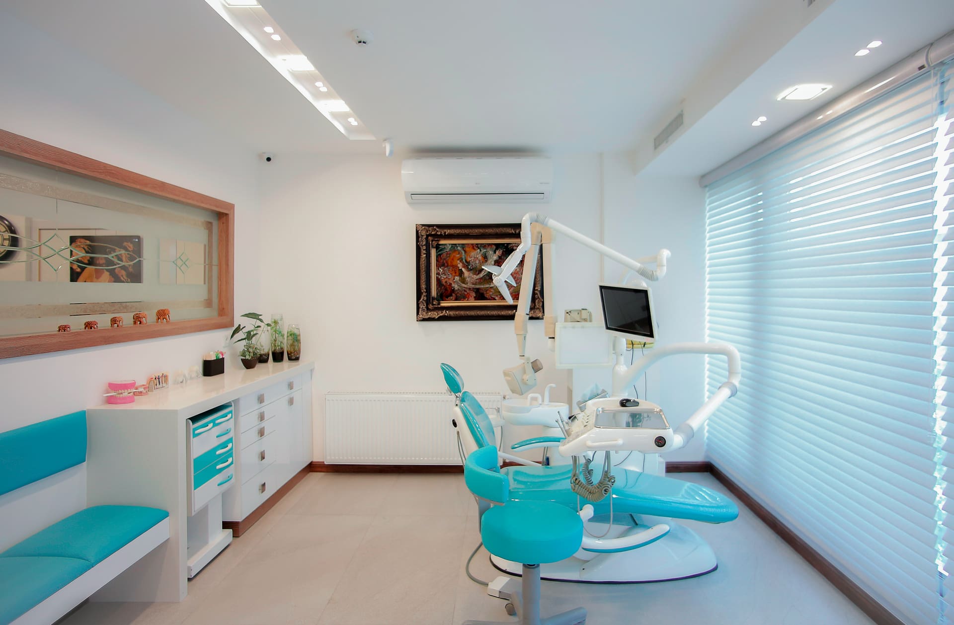Modern dental treatment room with a teal dental chair and equipment